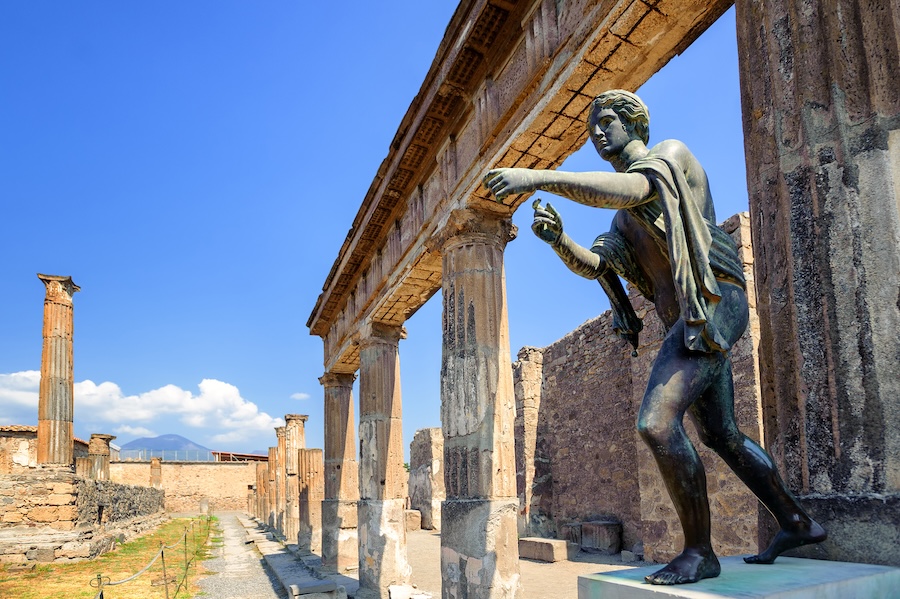 Ruins of the ancient Temple of Apollo with a bronze statue of Apollo in Pompeii, near Naples, Italy, a city famously destroyed by the eruption of Mount Vesuvius in 79 AD.