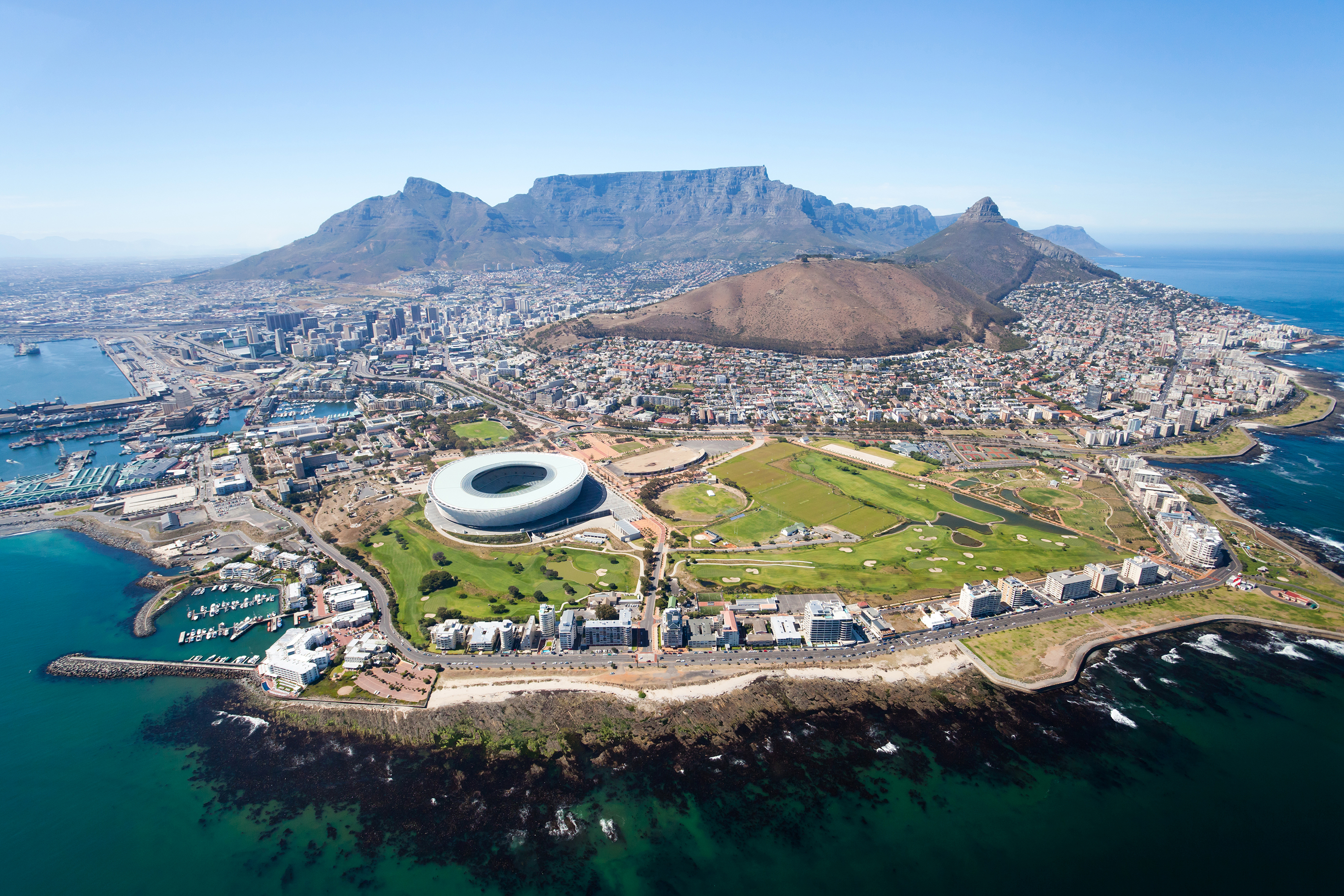 Aerial view of Cape Town with Table Mountain, coastline, and stadium.