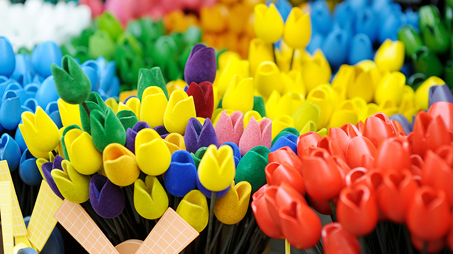 Vibrant display of colorful wooden tulips in shades of red, yellow, blue, green, and purple, arranged closely together, conveying a cheerful atmosphere.