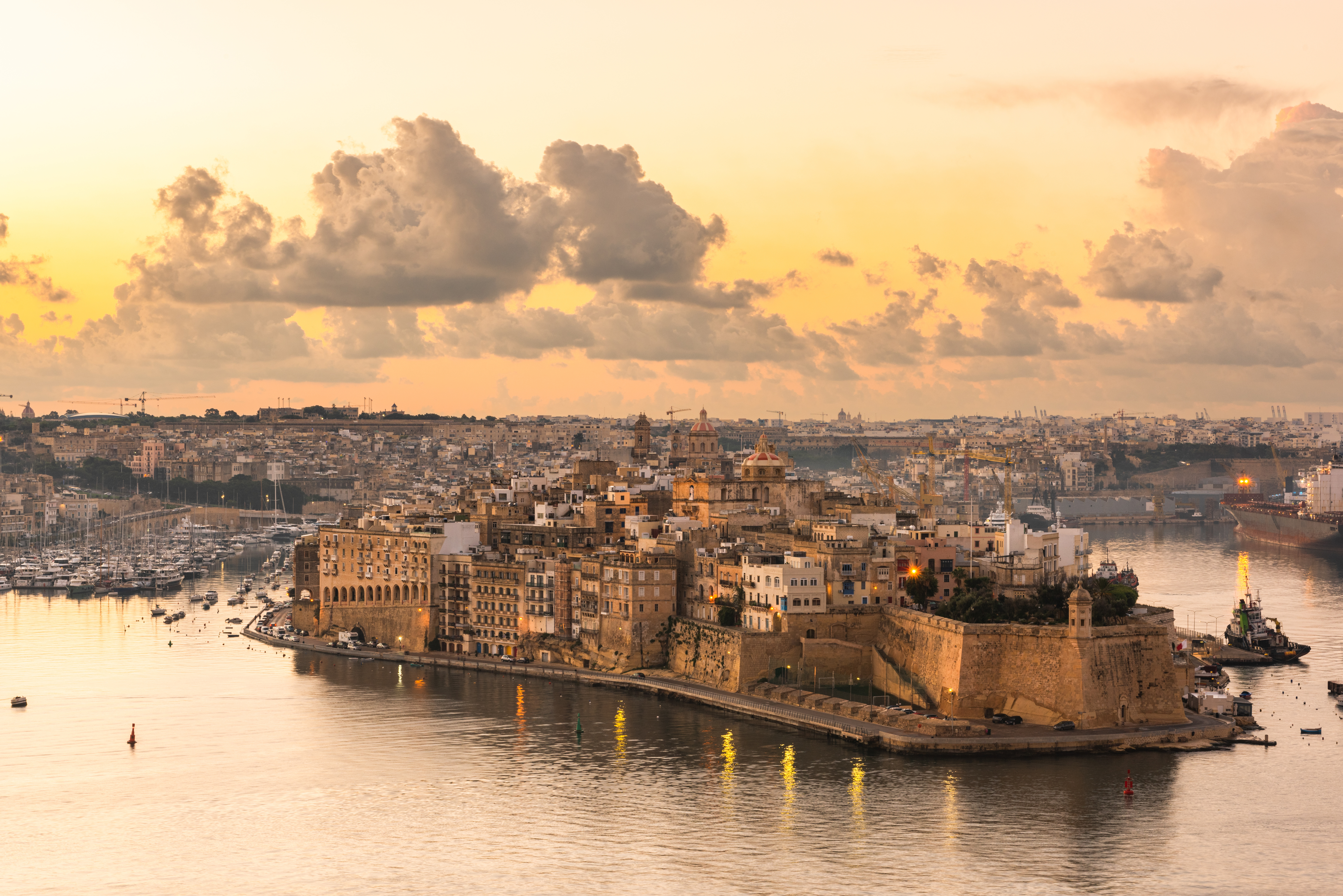 Sunset view of the Three Cities waterfront across Grand Harbour, Malta.