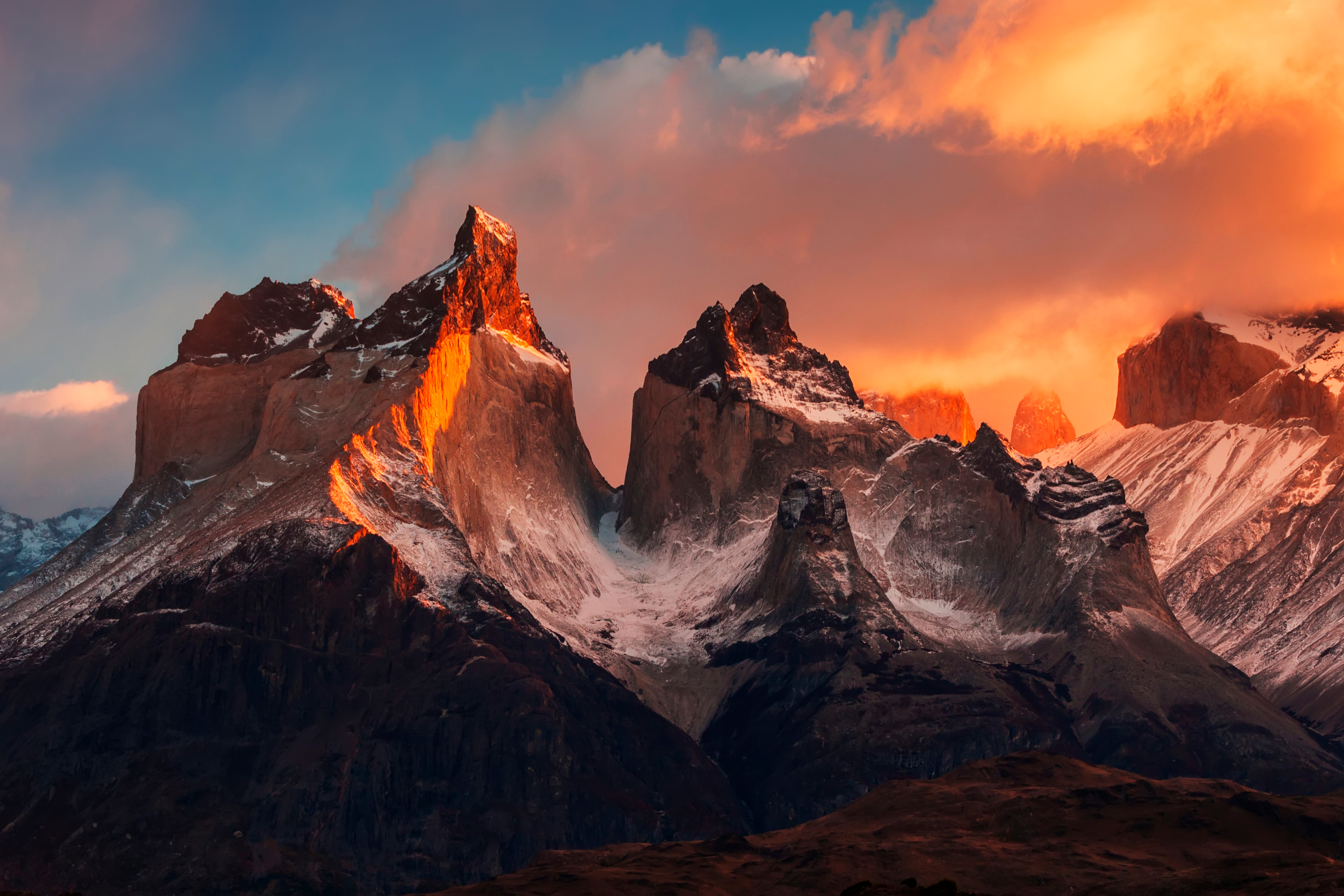 Sunrise over Torres del Paine National Park in Chile, highlighting the snow-capped peaks of the Cordillera Paine mountain range bathed in warm morning light.