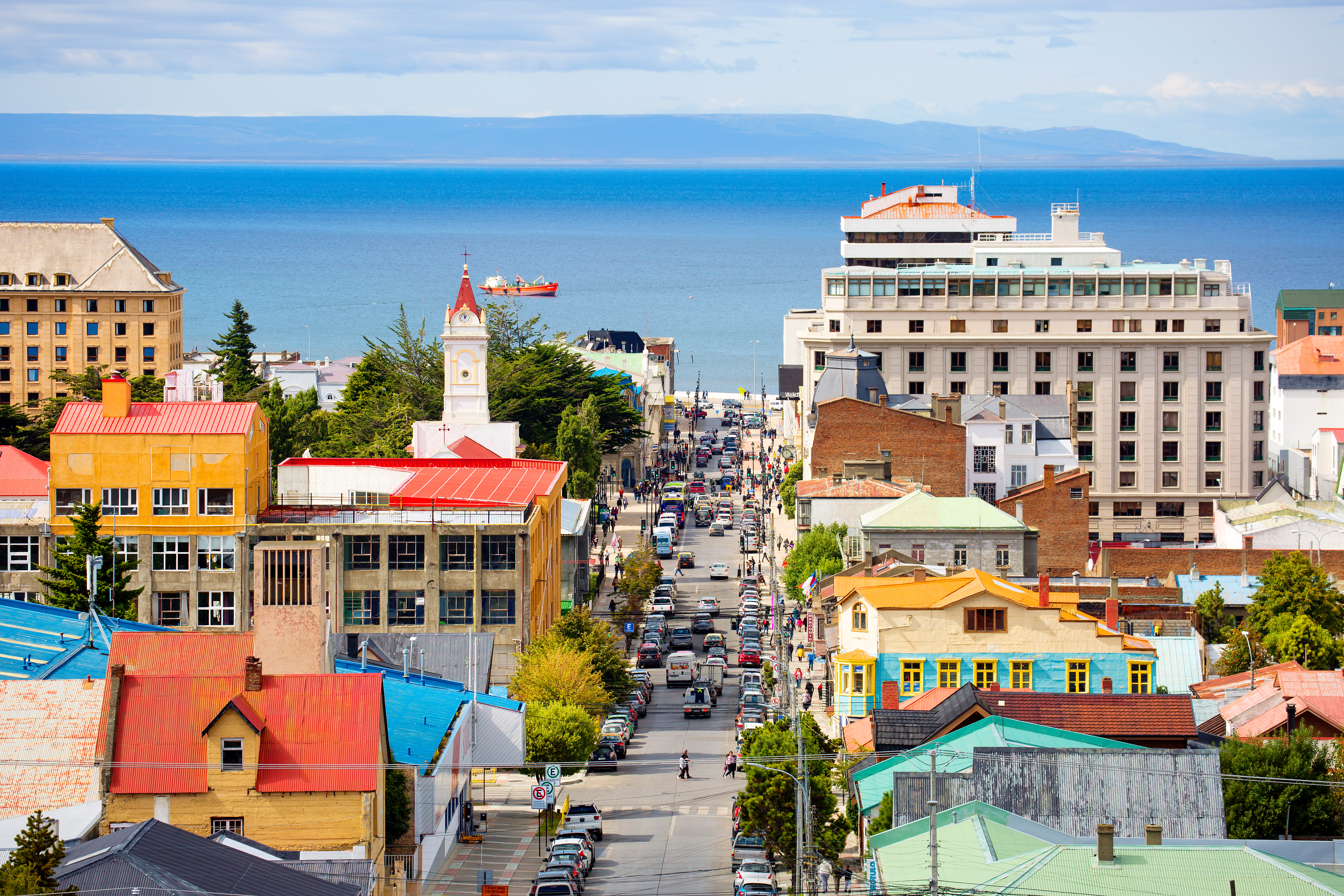 Cityscape of Punta Arenas, Chile, viewed from a vantage point overlooking the Strait of Magellan, with the city’s Cathedral visible slightly left of center amid the urban landscape.