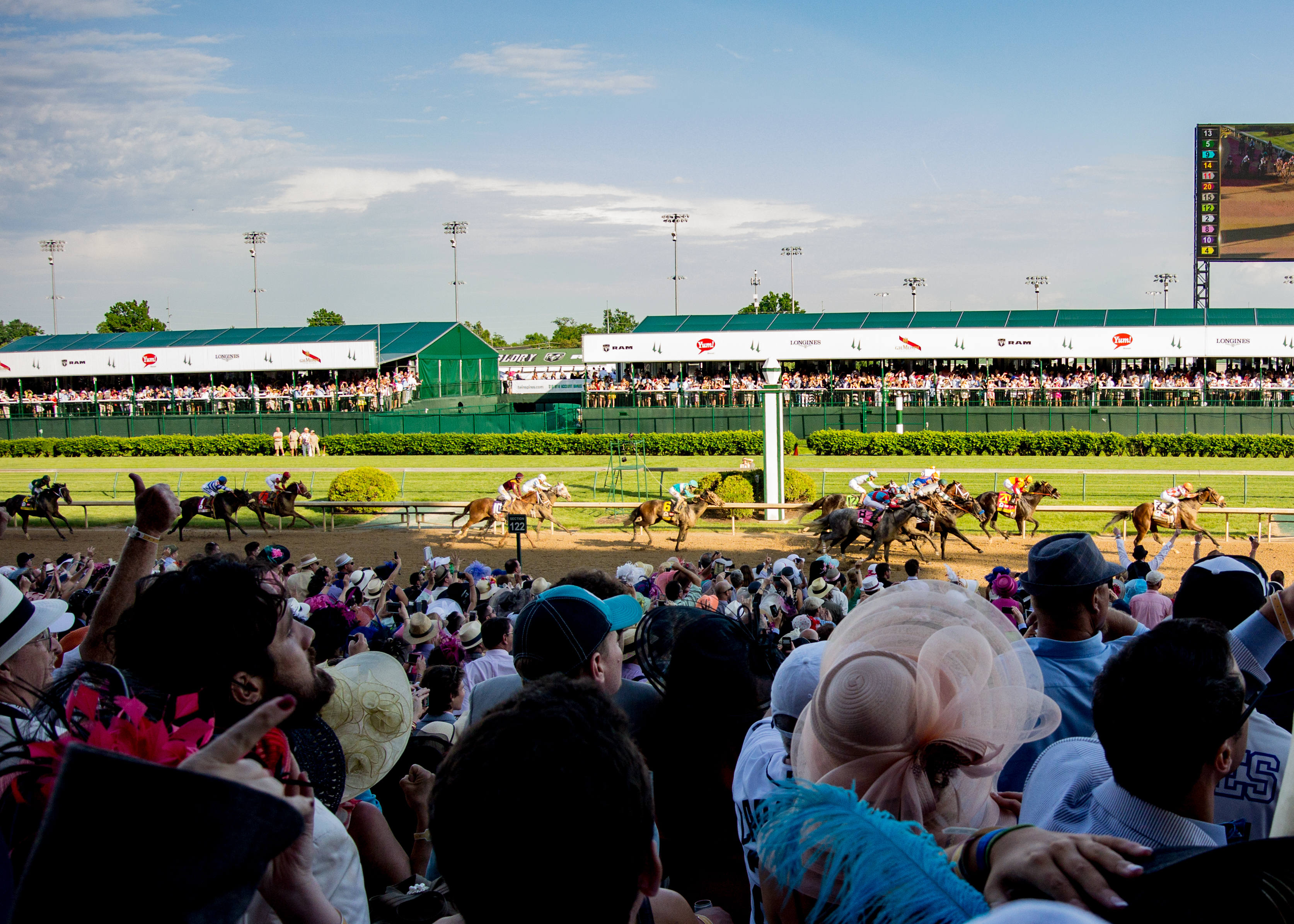 Thoroughbred horse race with a large crowd watching from the grandstand at a racetrack.