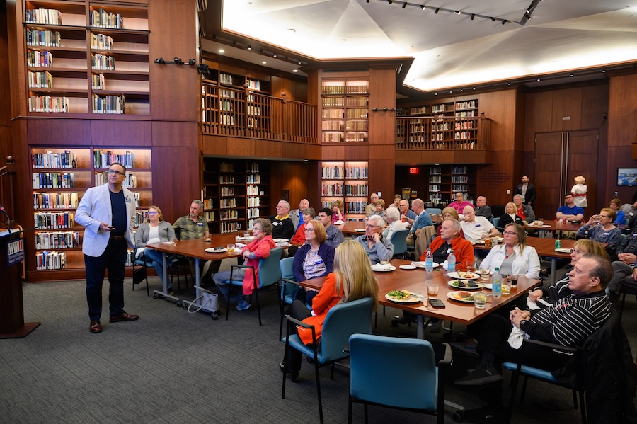 A room filled with books and people listening to a lecture