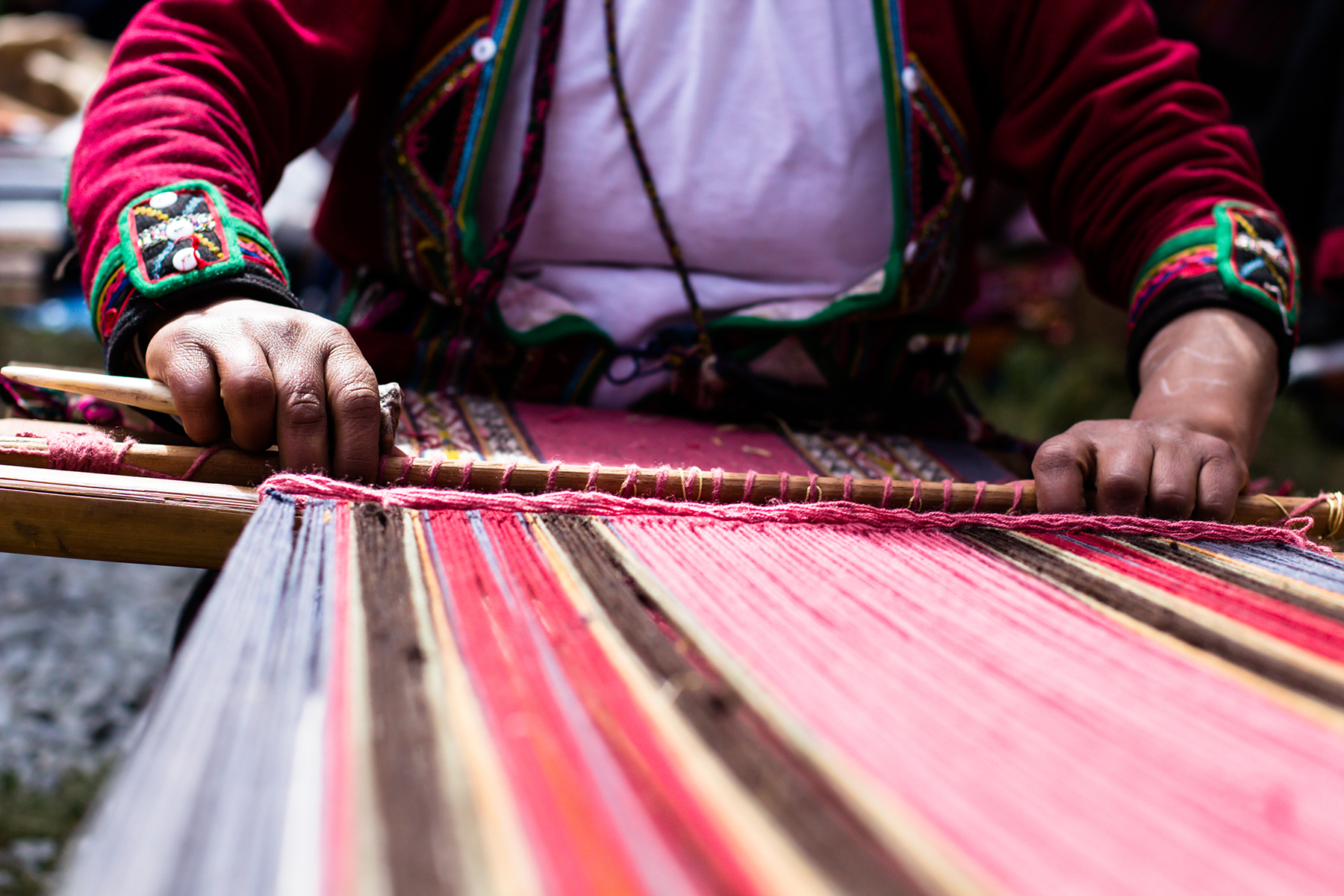 Close-up of traditional hand weaving in the Andes Mountains, Peru, showing colorful yarns and skilled hands creating intricate patterns on a loom.
