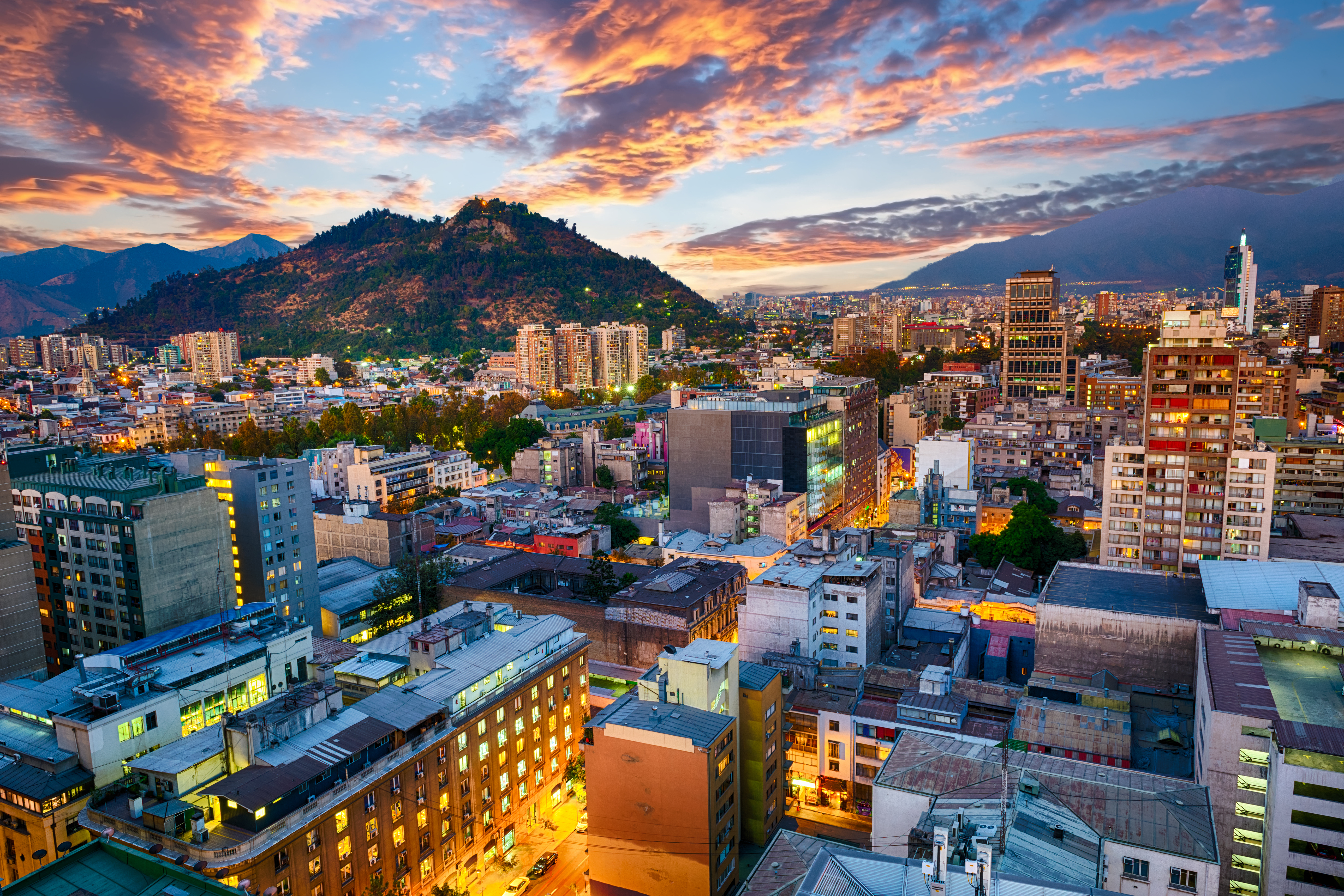 Downtown Santiago de Chile illuminated after sunset, with city lights glowing against the twilight sky.