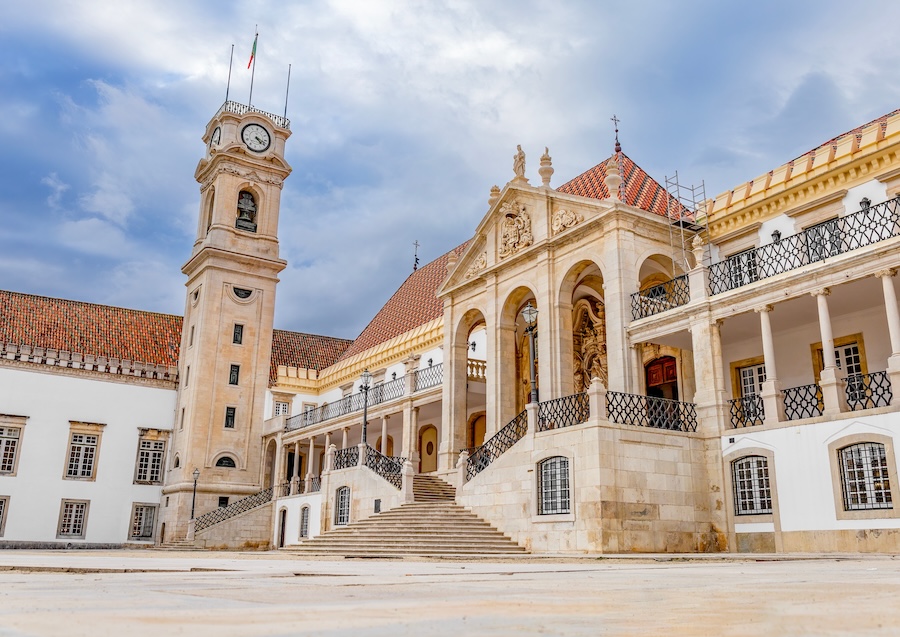 Historic University of Coimbra in Portugal, featuring a clock tower, grand staircase, and ornate architecture.