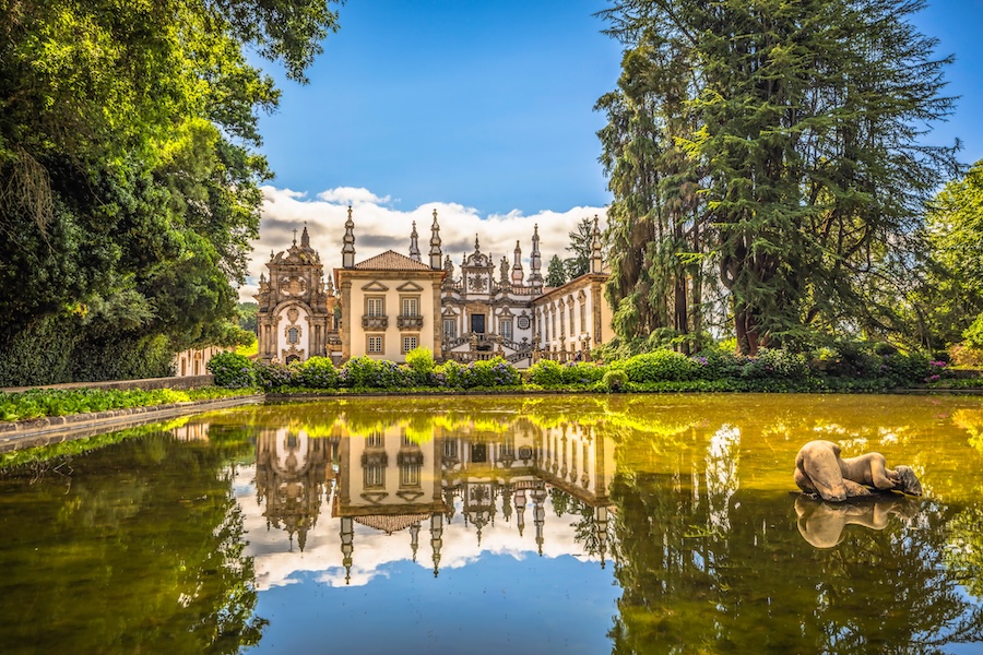Majestic Baroque-style Palace of Mateus in Portugal, with ornate architecture, gardens, and reflective pond.