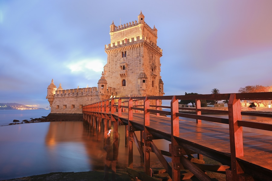 Belém Tower in Lisbon, Portugal, a historic fortress with Manueline architecture, illuminated at twilight by the waterfront.