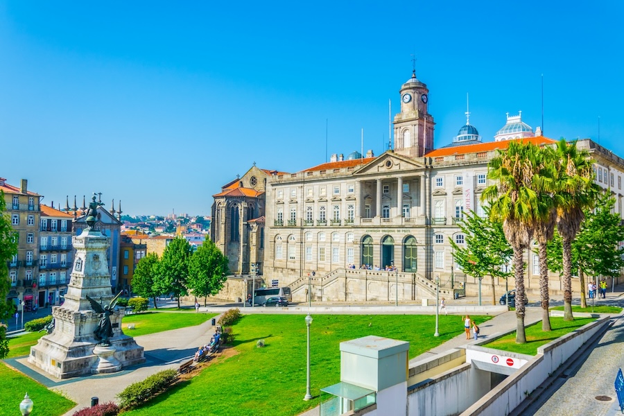 Palácio da Bolsa in Porto, Portugal, a neoclassical landmark with a clock tower, surrounded by gardens and monuments.