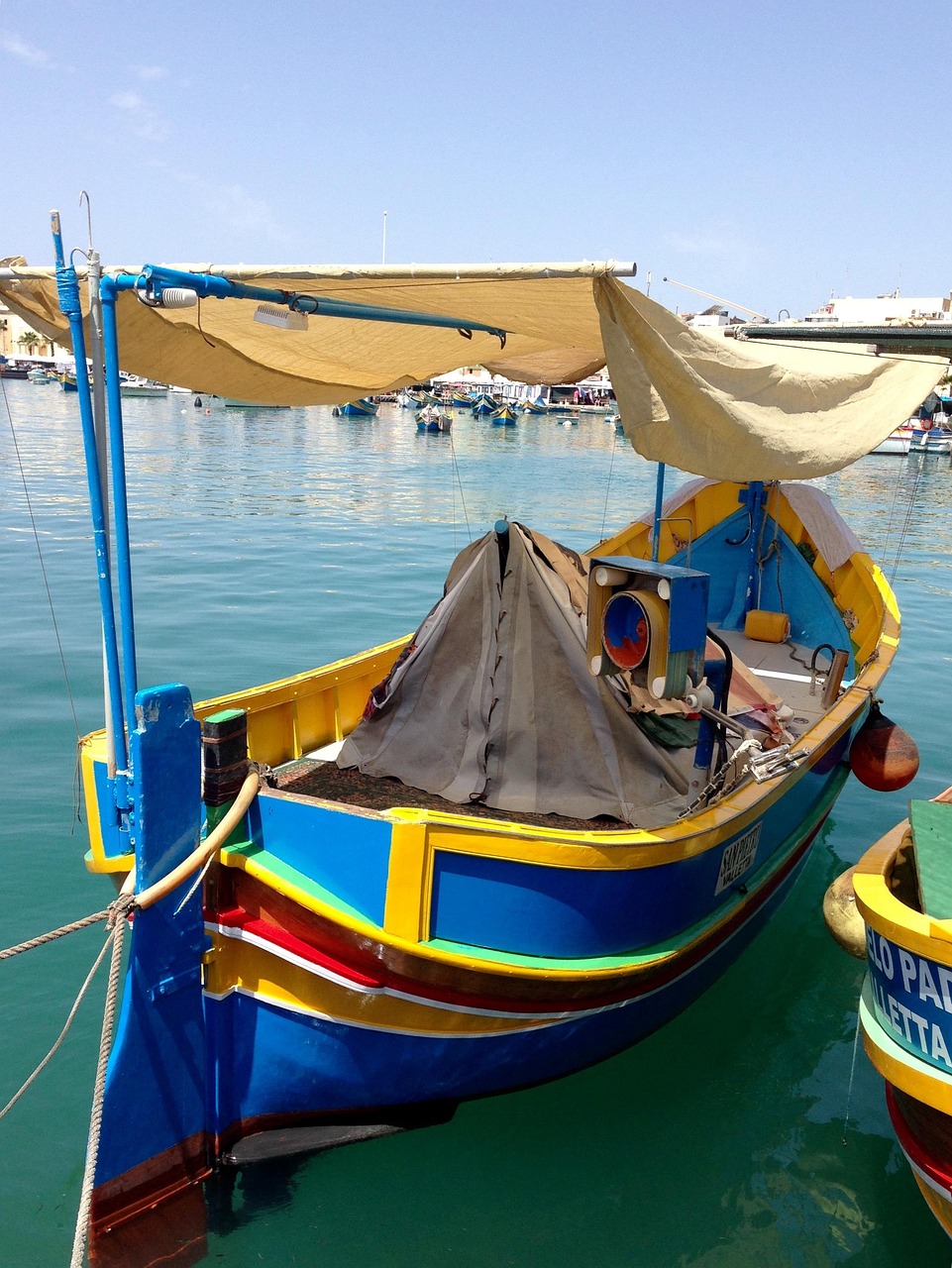 Traditional Maltese luzzu fishing boat moored in Marsaxlokk harbor.