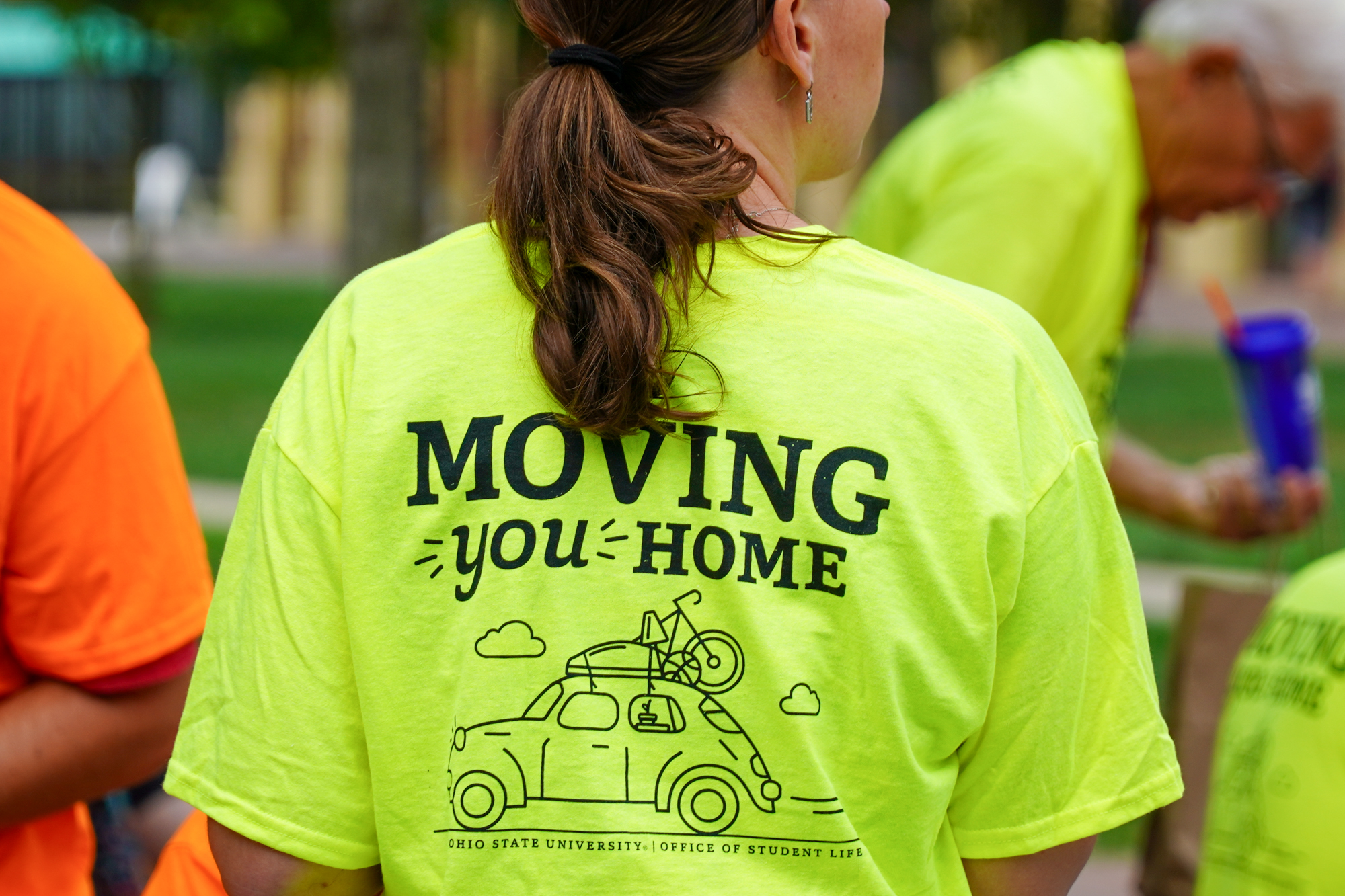 move-in volunteer wearing a green shirt with the text moving you home on the back in black font