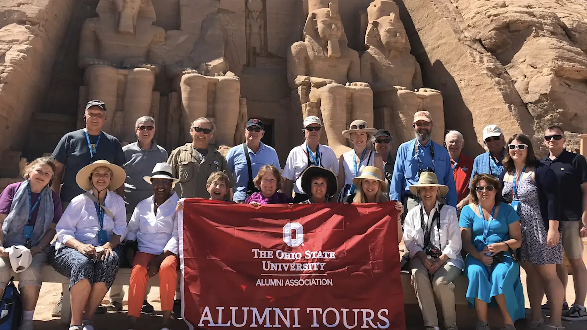 group of ohio state alumni holding an ohio state banner in front of Egyptian statues