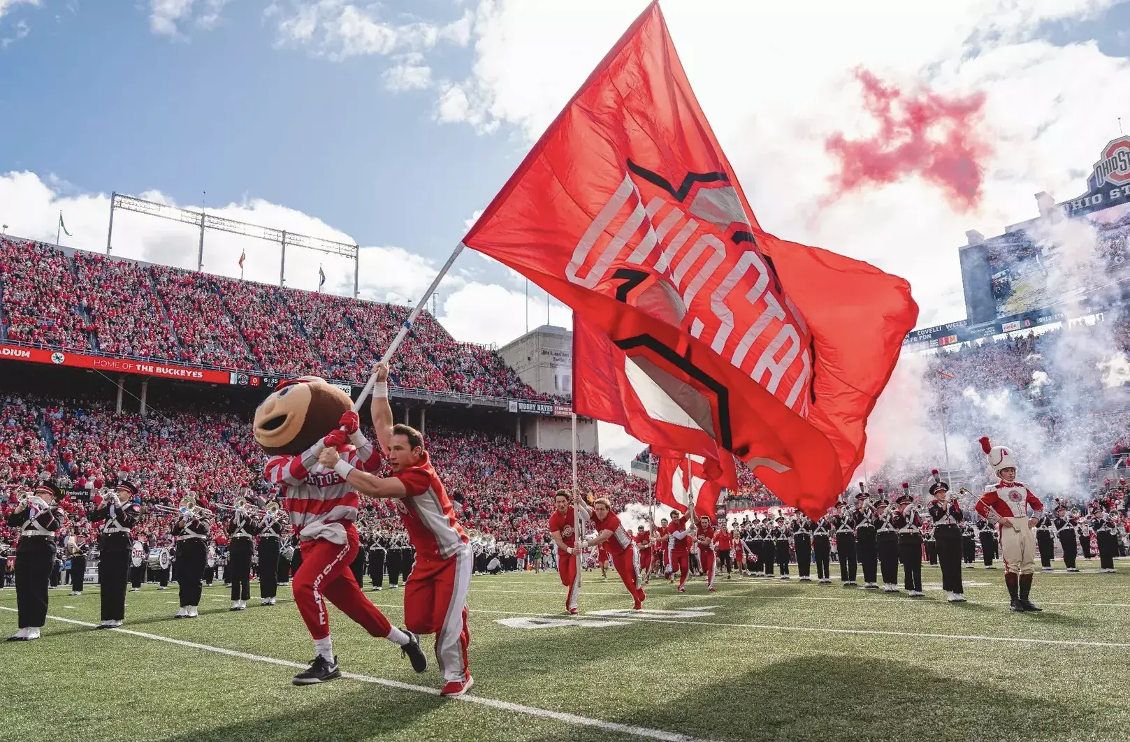 brutus buckey carrying ohio state flag out on the football field