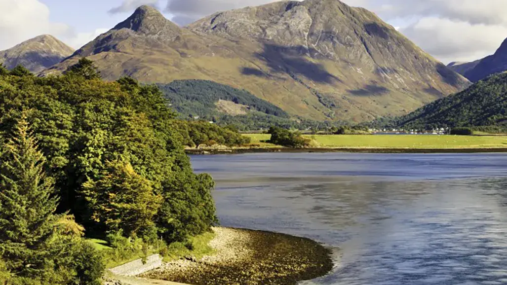 lush green scotland with mountains and large body of water in the foreground