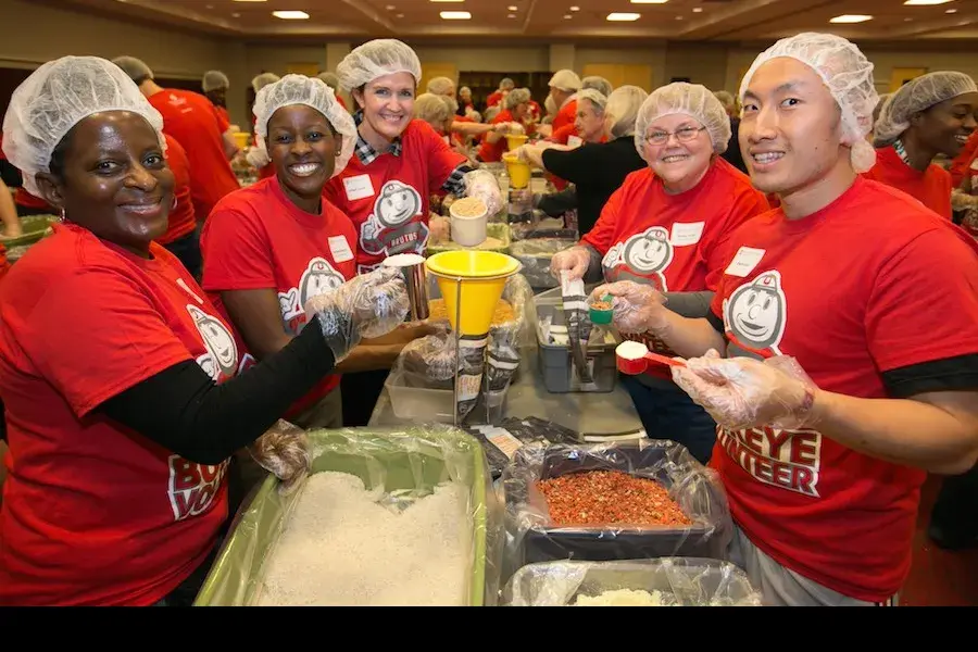 five people pack meals at a volunteer event