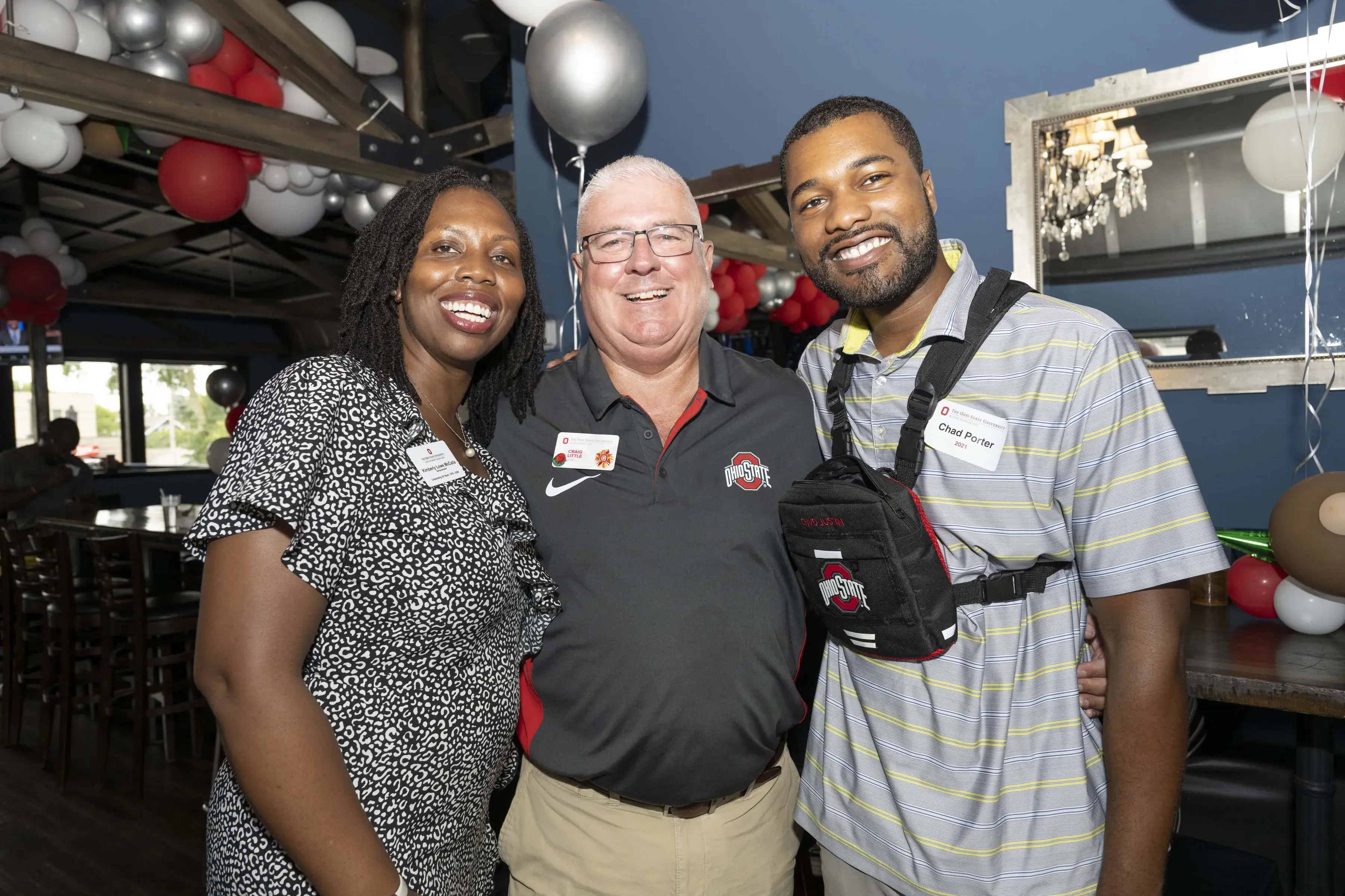 three people stand smiling arm in arm