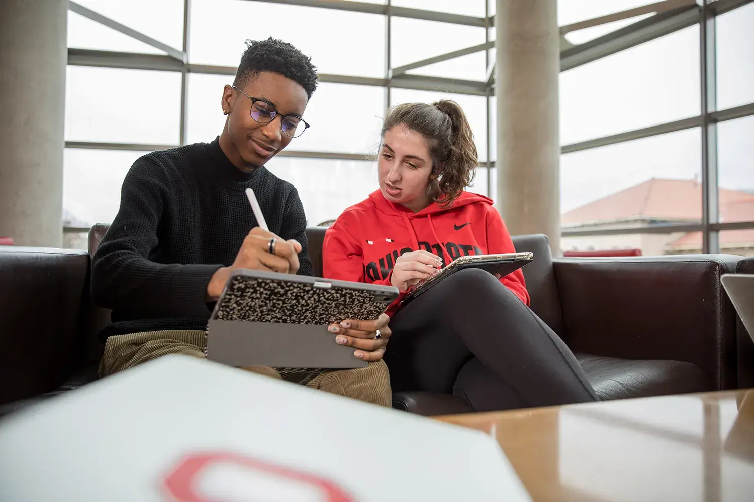 two people taking notes on an ipad