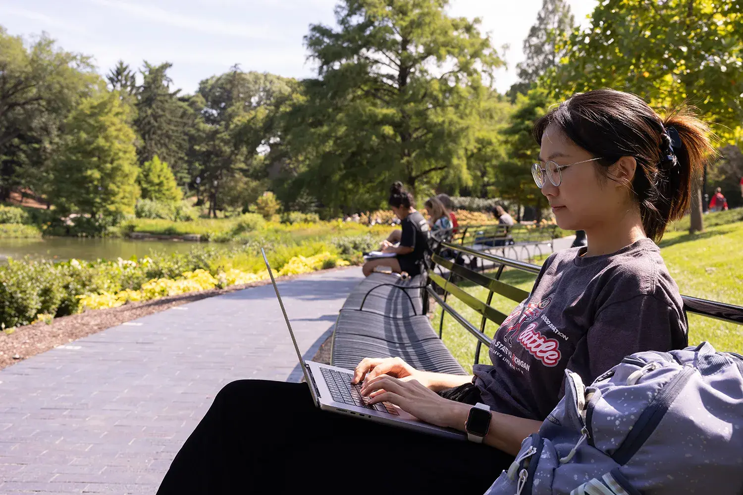 woman using laptop while sitting on a bench