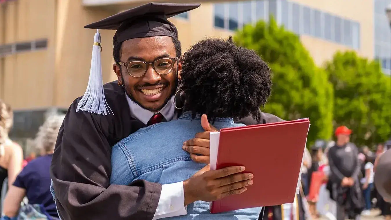 a college graduate hugs his mother