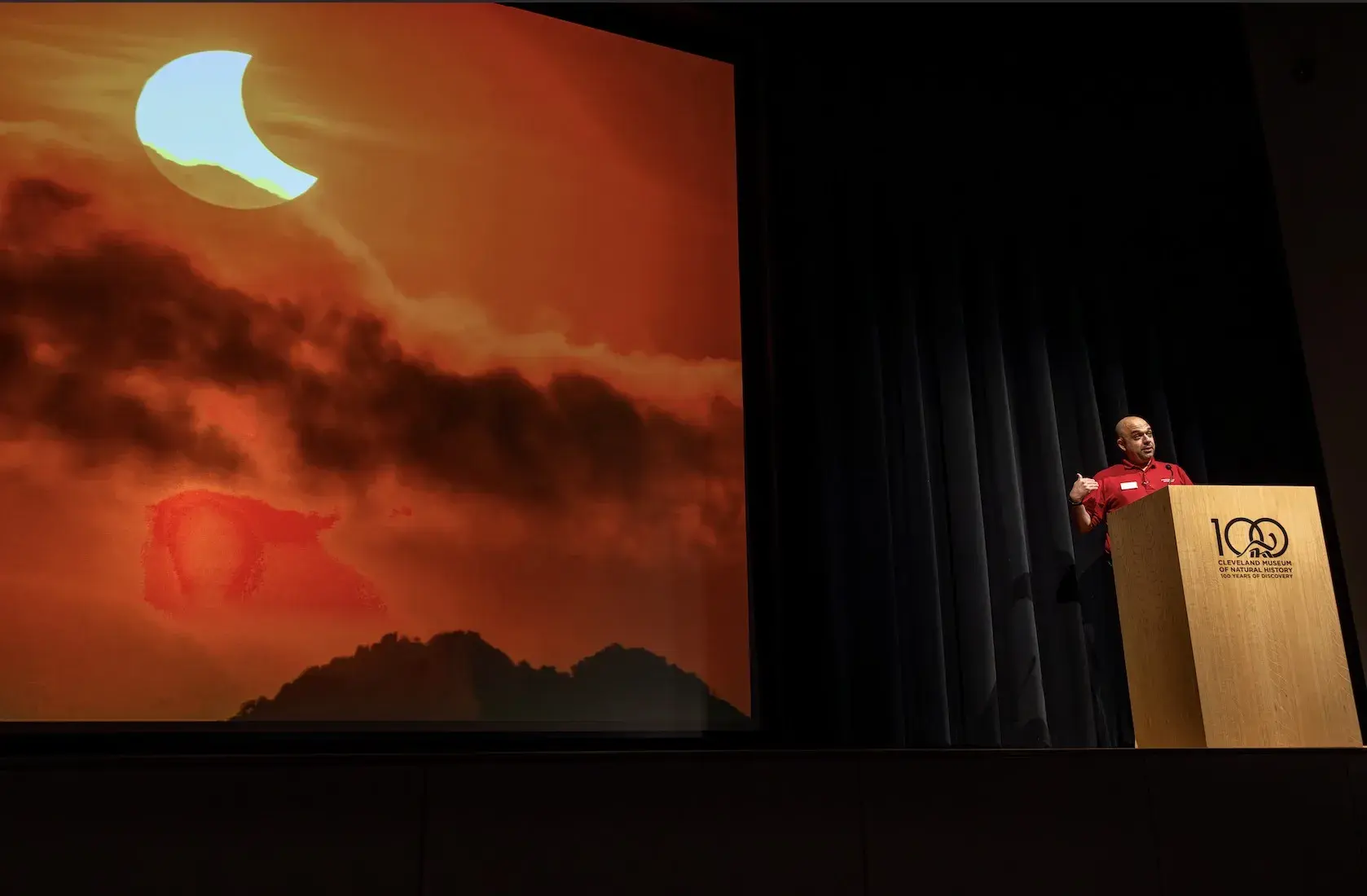 man stands on stage behind a podium