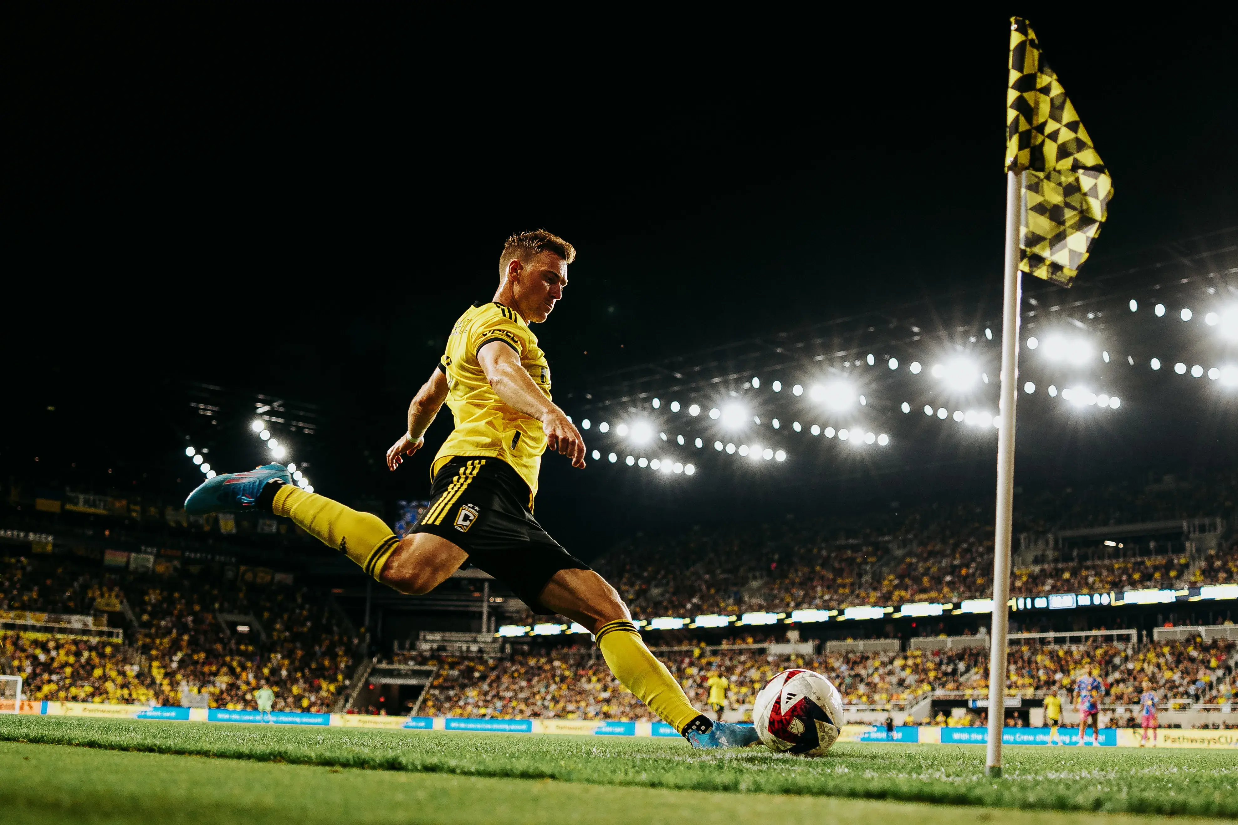 A Crew player kicking a soccer ball during a Crew night game