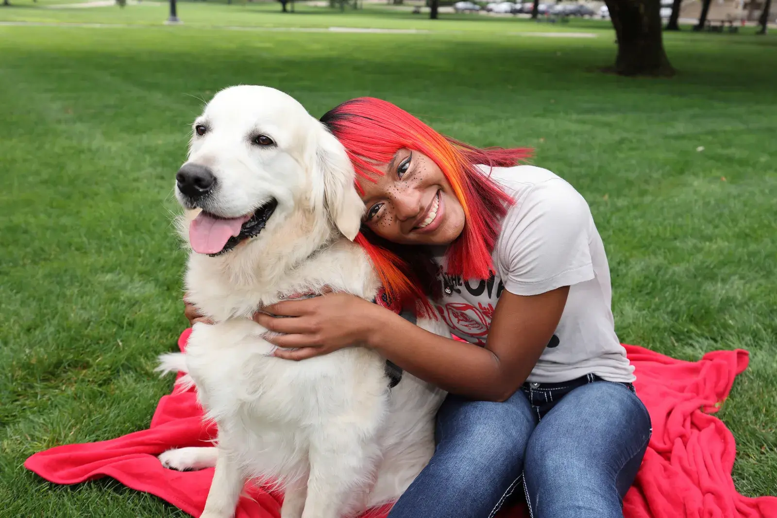 a white-coated dog sits next to a woman