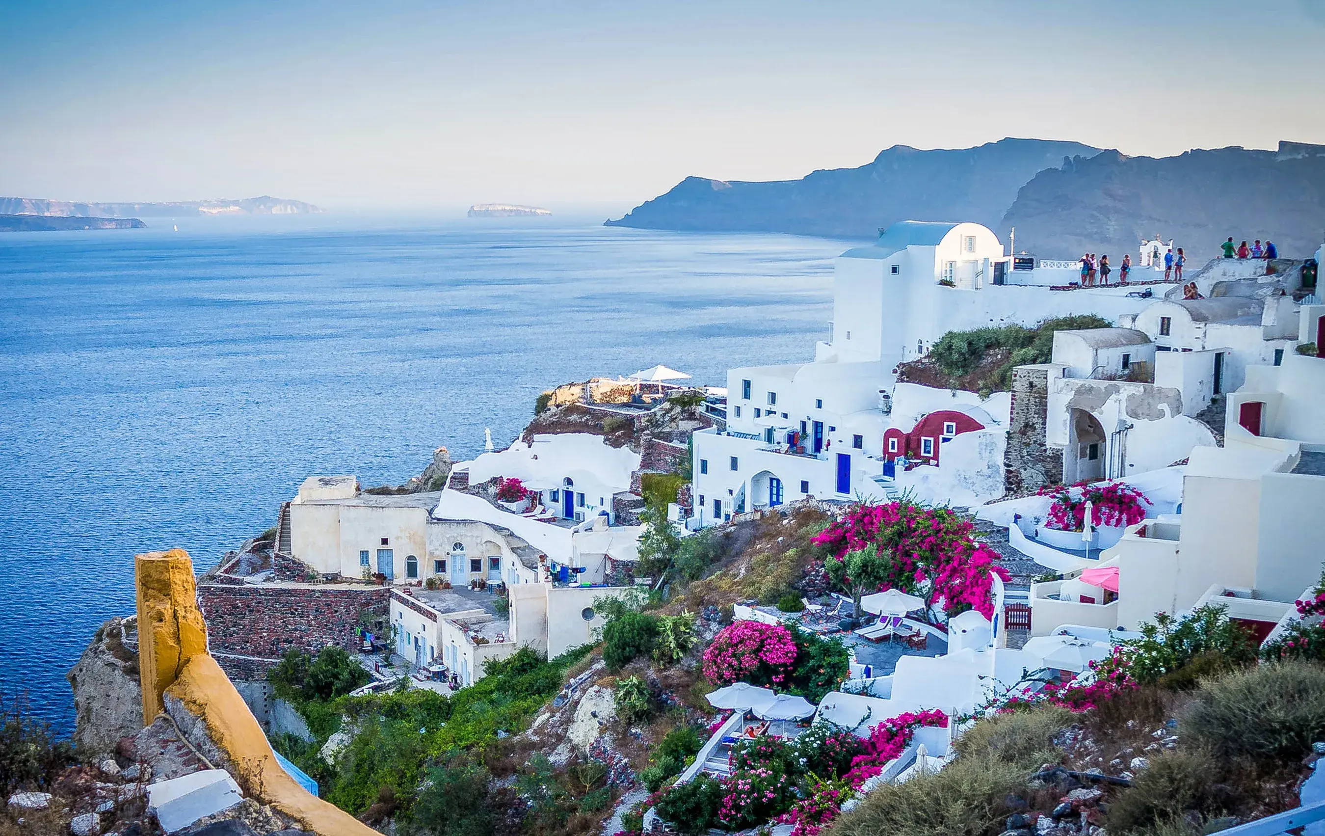 White buildings nestled on a cliff next to the Aegean Sea