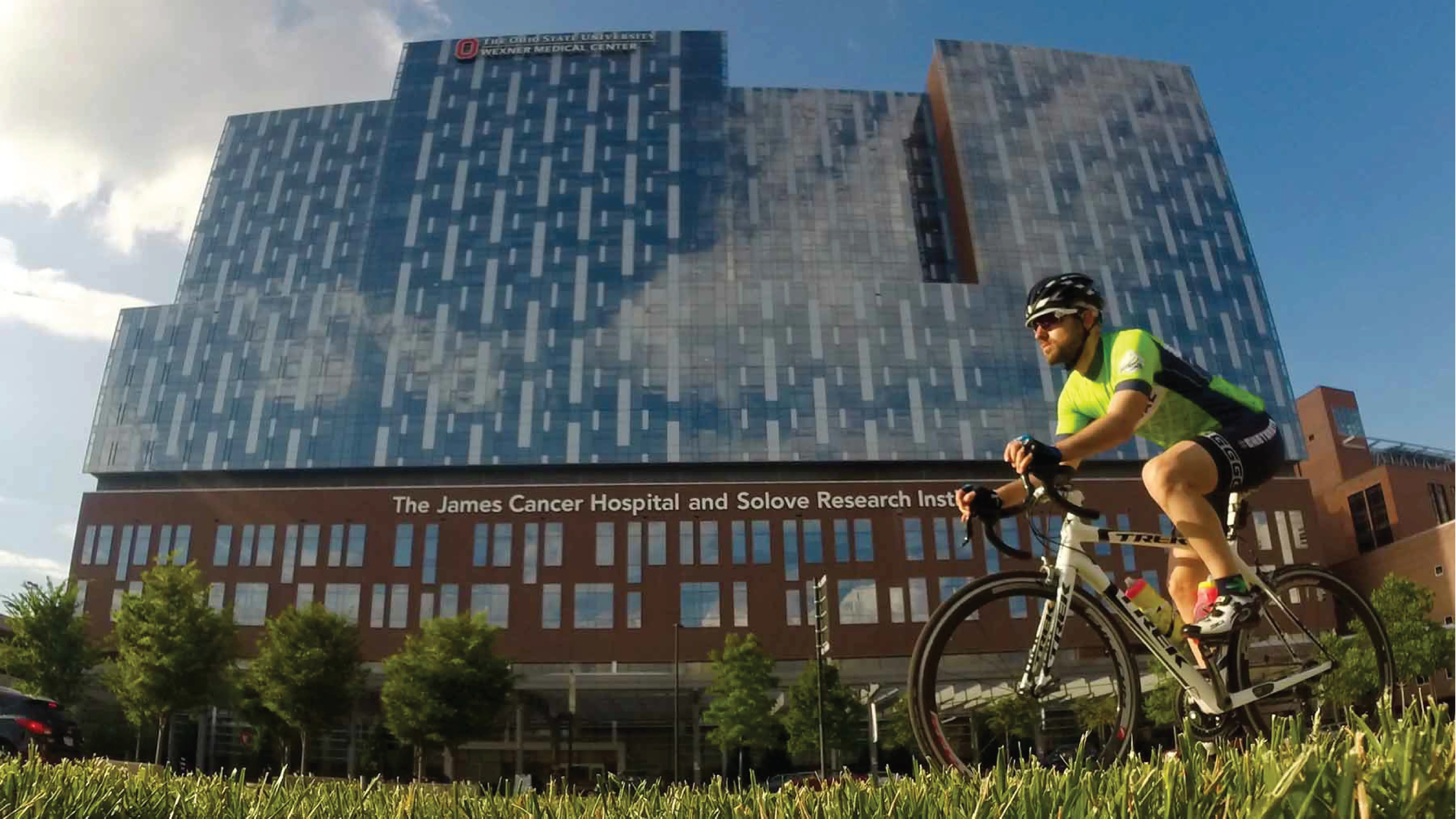 bike rider pedals in front of a hospital building