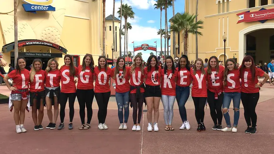 the dance team alumni posing for a picture with shirts that say "Let's go buckeyes"