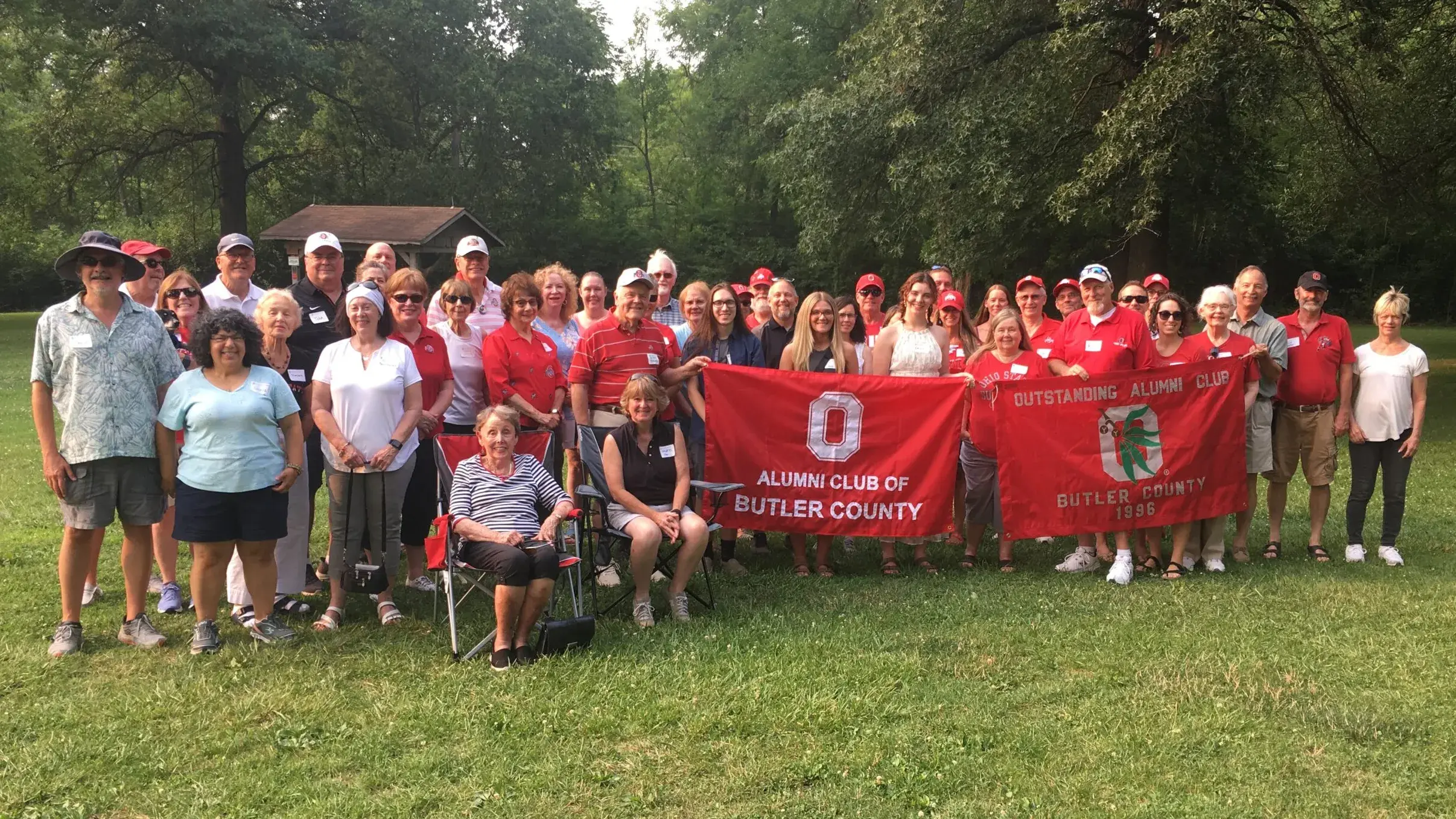 large group of osu alumni holding buckey banners posing for a picture outdoors