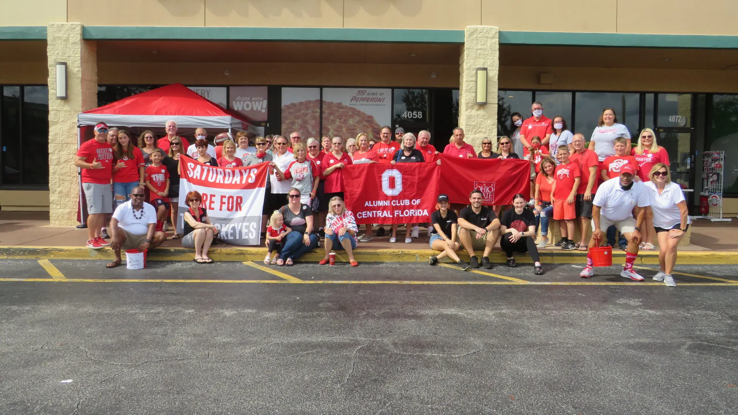 group of ohio state alumni holding OSU banners in front of donatos