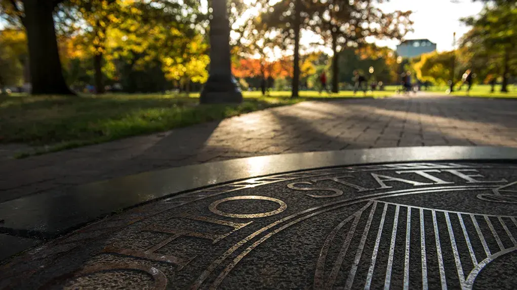 Ohio State seal with evening sun shining through the trees