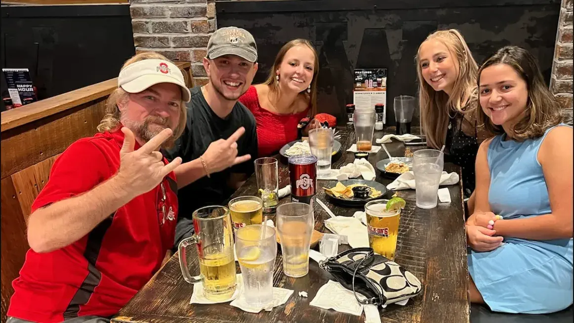 group of ohio state alumni sitting at a table in a restaurant posing for a photo