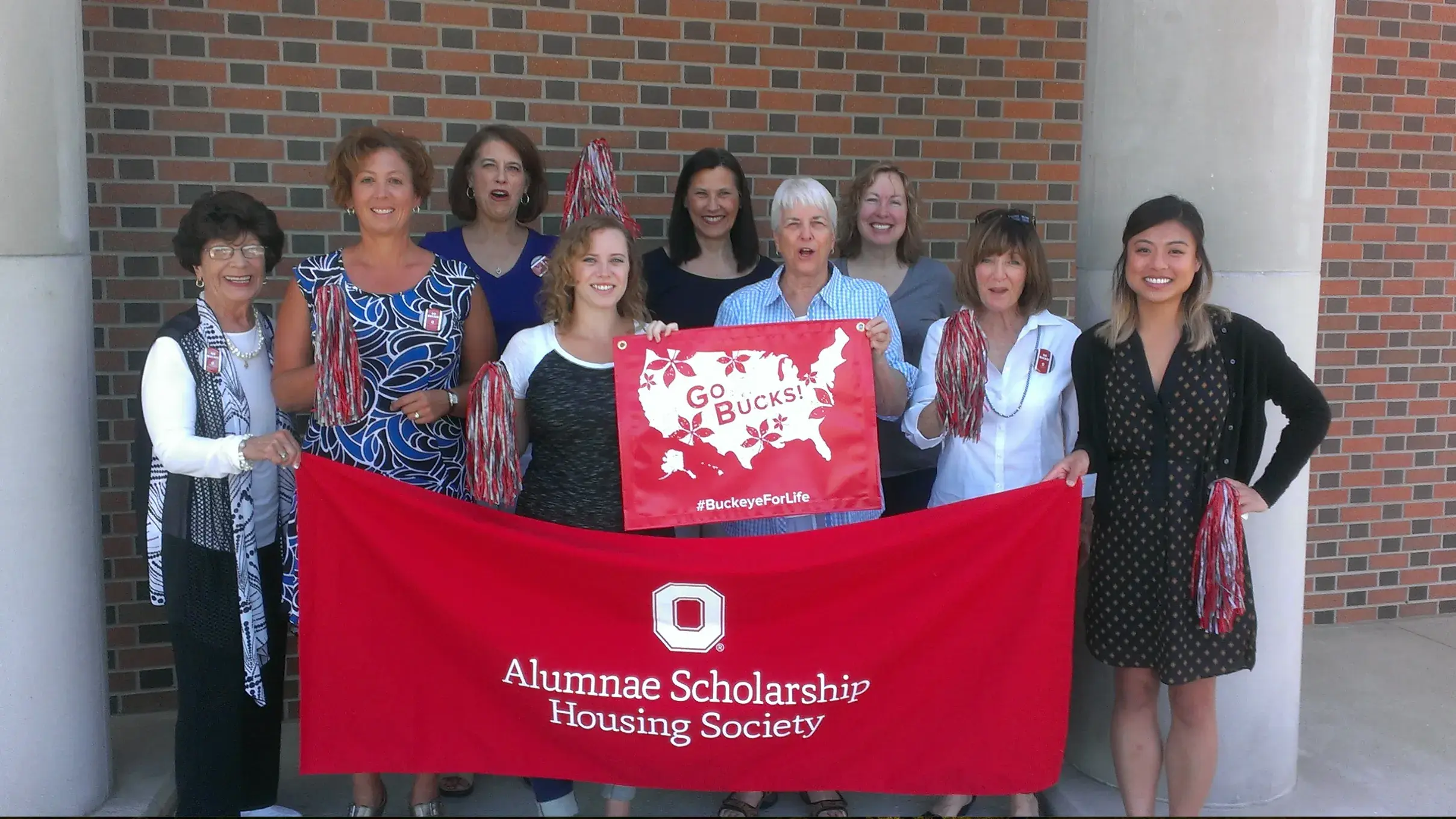 ohio state alumni holding a red ohio state banner while posing for a photo