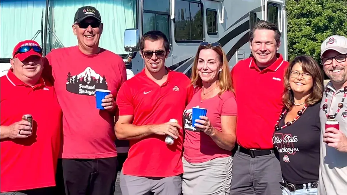 small group of ohio state alumni wearing red shirts posing for a photo in front of an RV