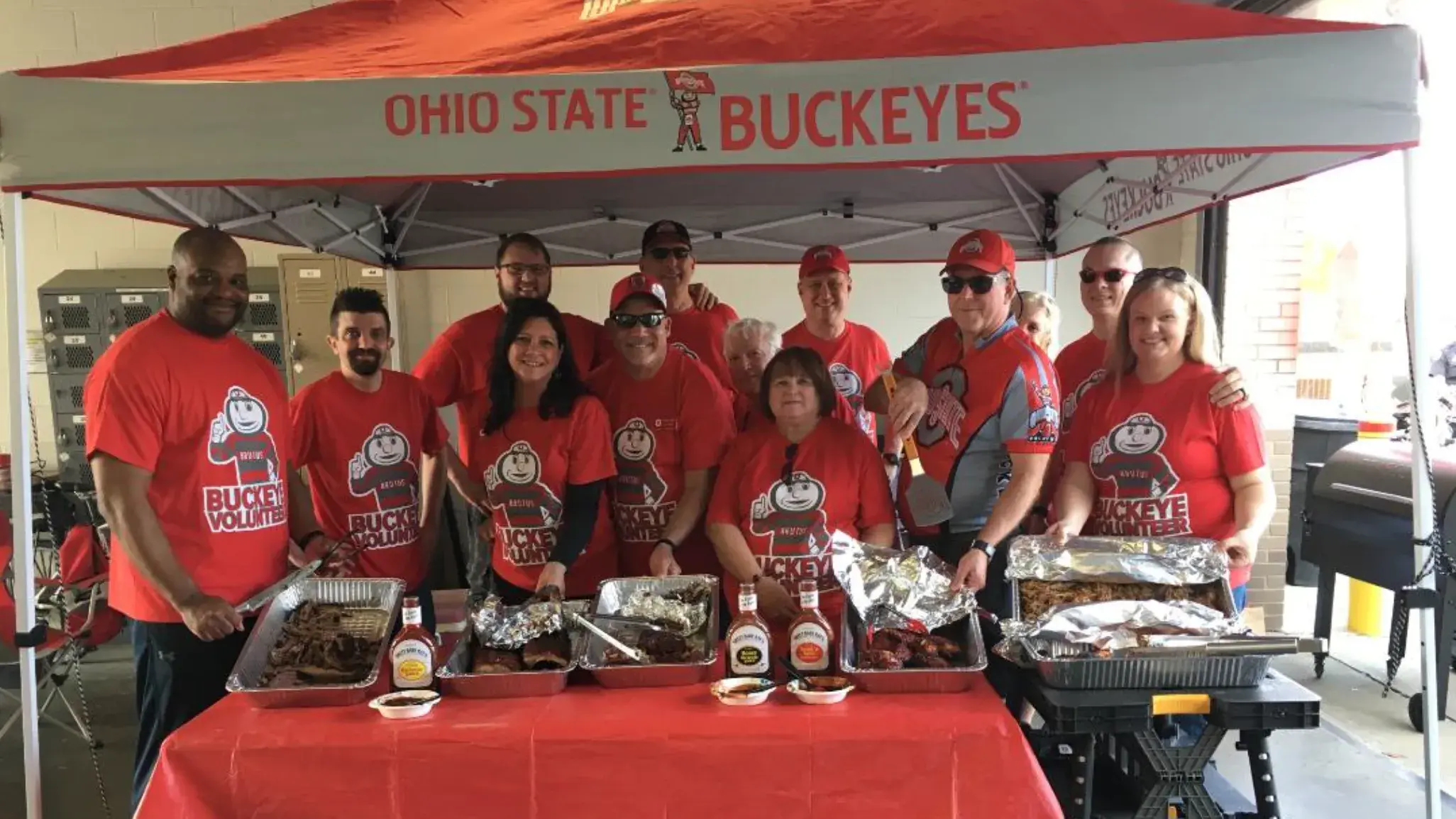 ohio state alumni posing with their tailgate bbq on gameday