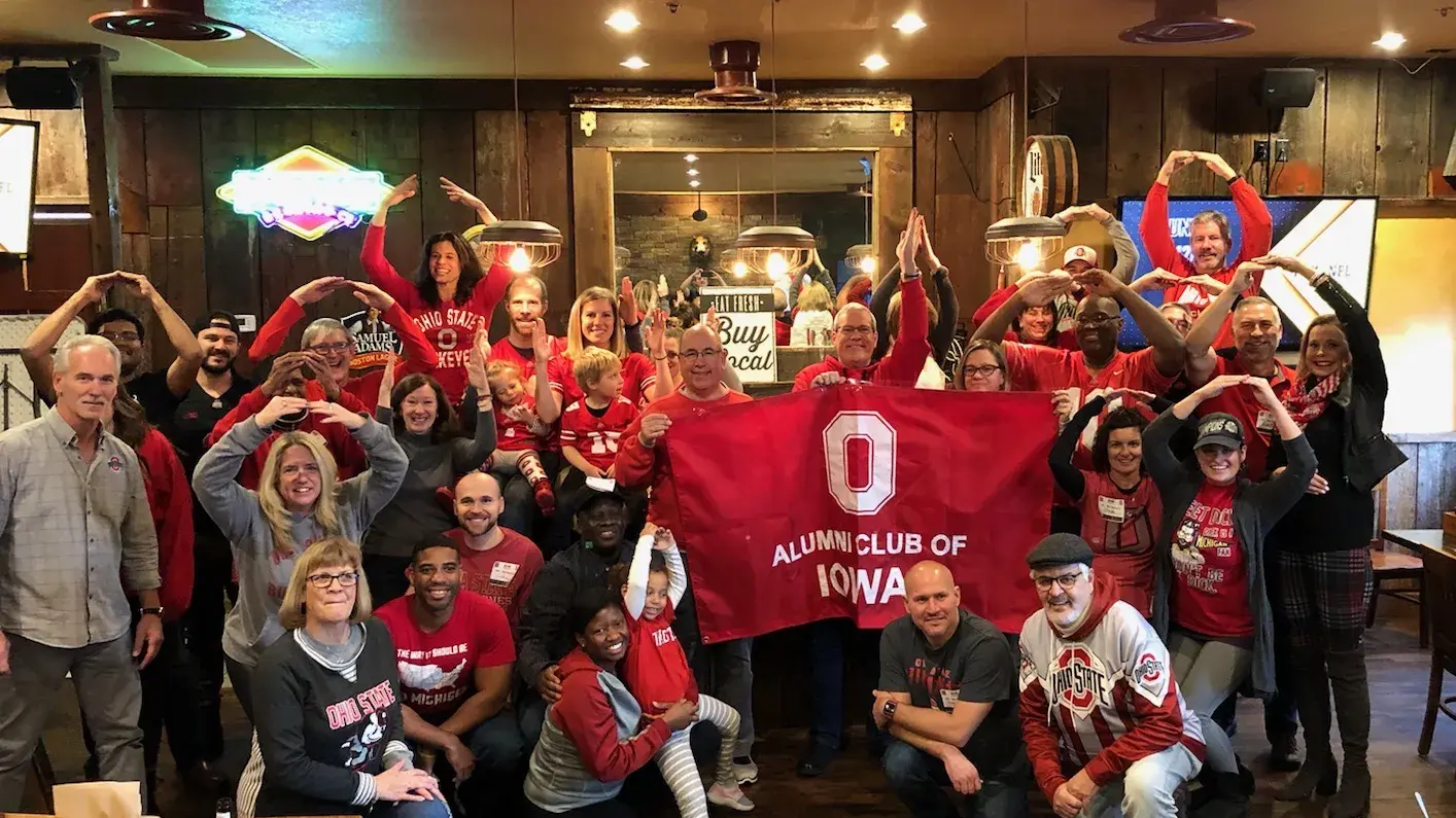 ohio state alum in red osu gear posing for a group picture at a bar