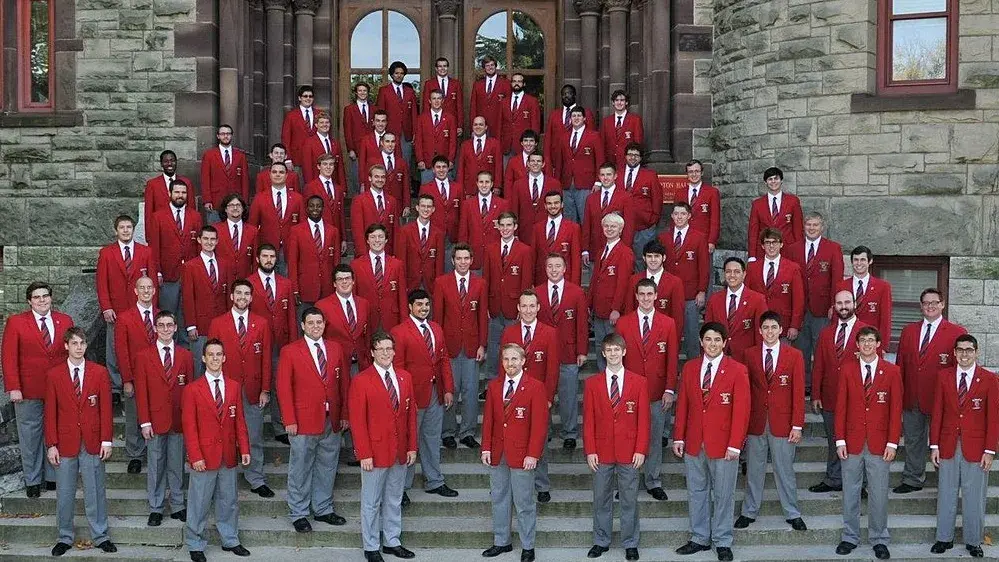 large group of ohio state alumni in gray pants and red suit jackets posing for a photo