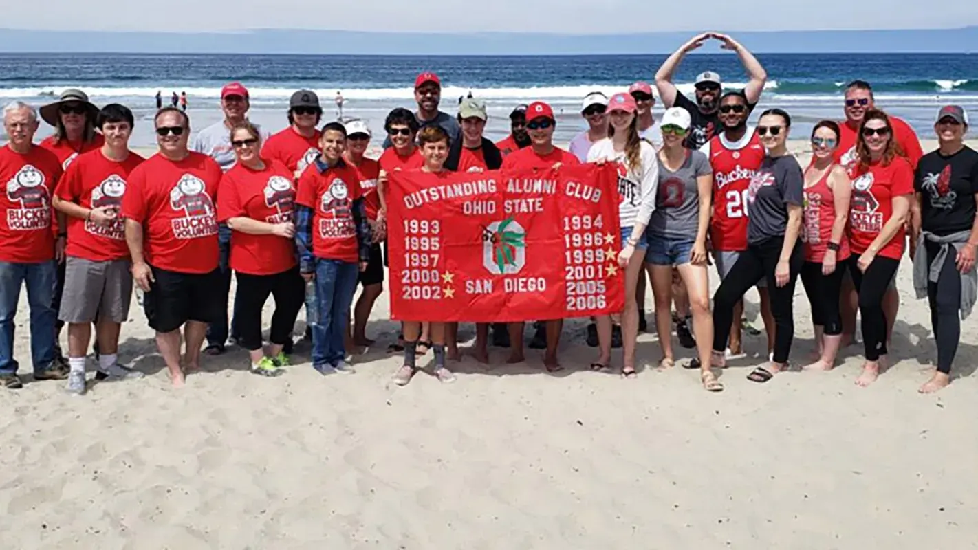 osu San Diego alumni holding an osu banner on the beach