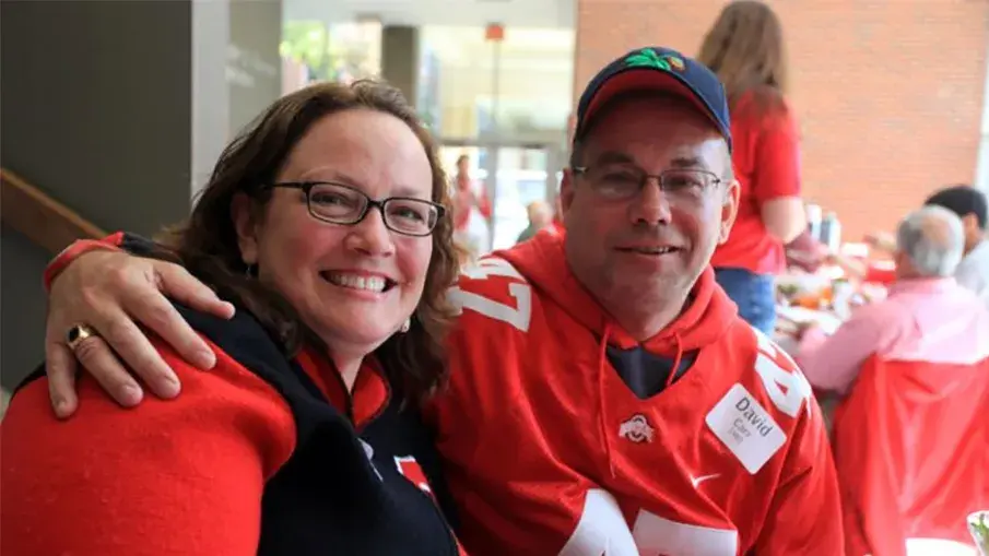 two people smiling while wearing ohio state apparel