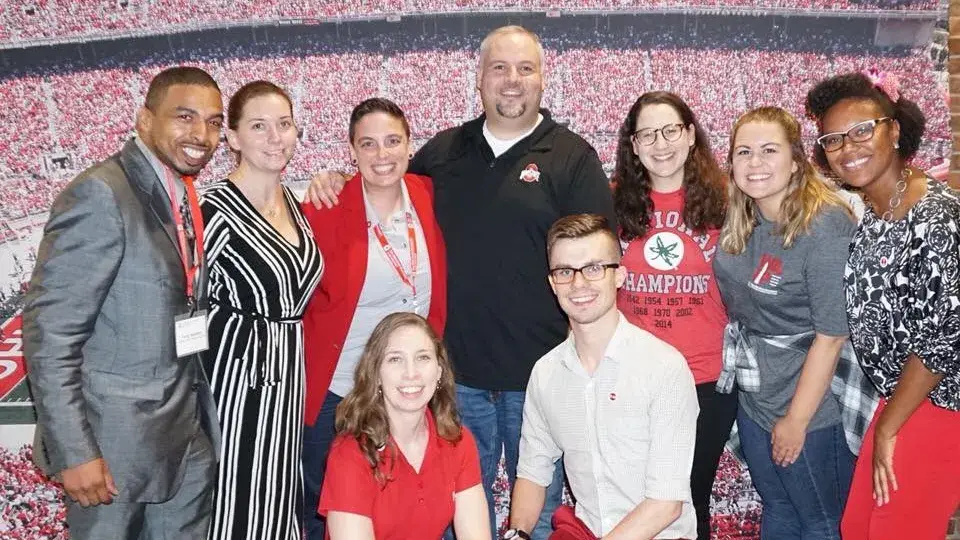 11 people wearing ohio state colors of scarlet, gray and black pose for a group picture