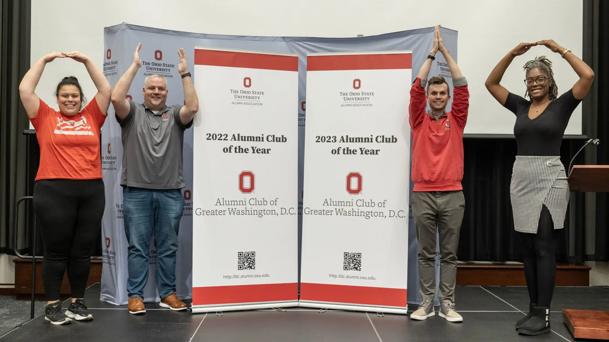 four people pose for o-h-i-o photo with club-of-the-year banners in between them