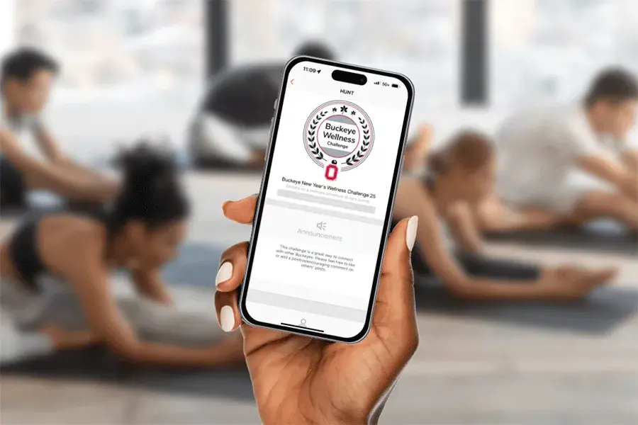 Buckeye Wellness app being displayed on a cell photo with a yoga class in the background