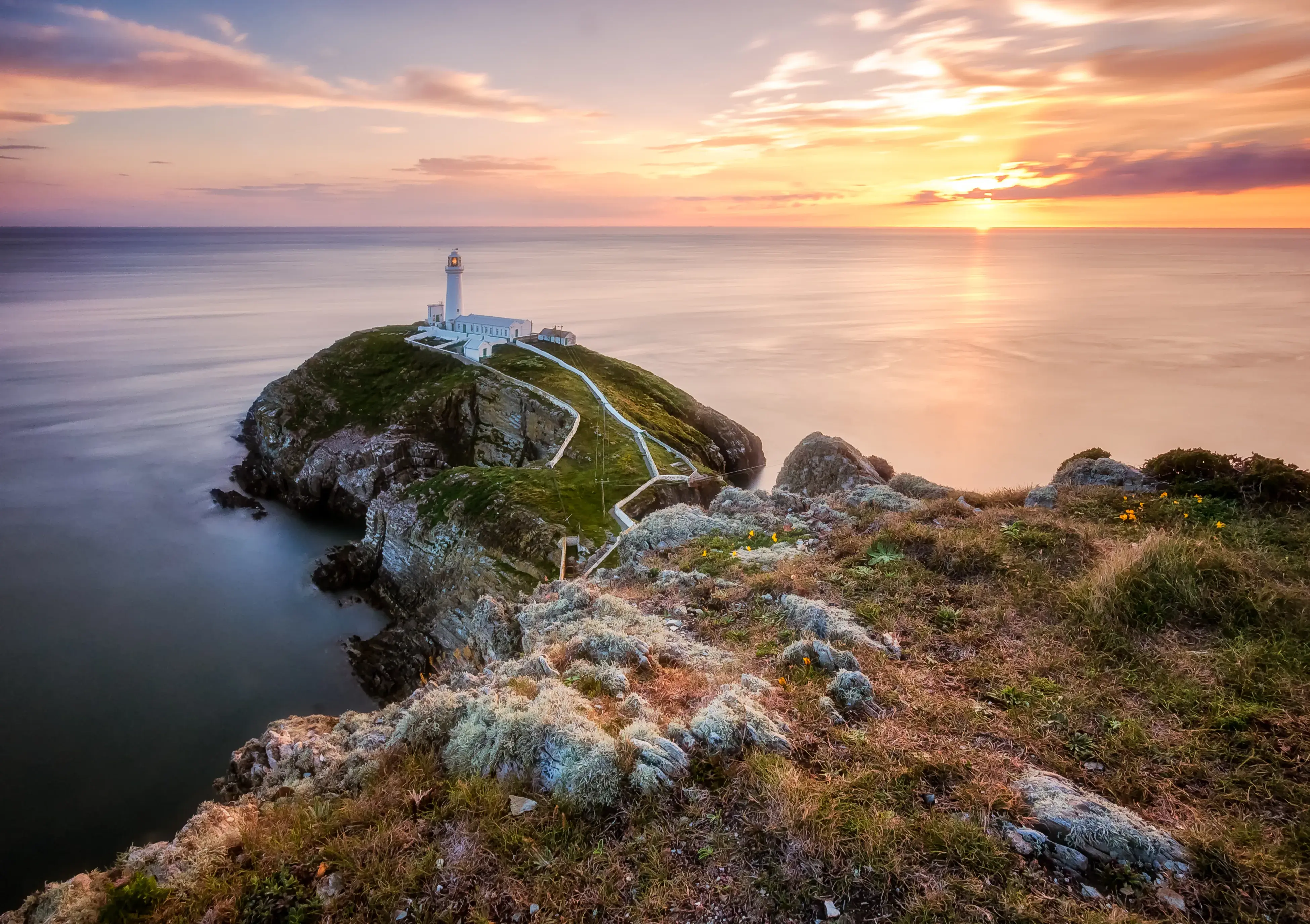 Lighthouse on a cliff overlooking the ocean at sunset