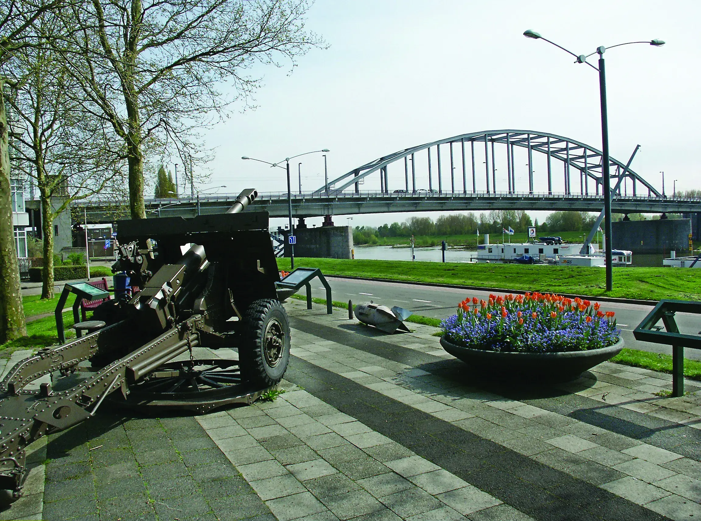 historical military equipment sitting outside near a bridge on a sunny day