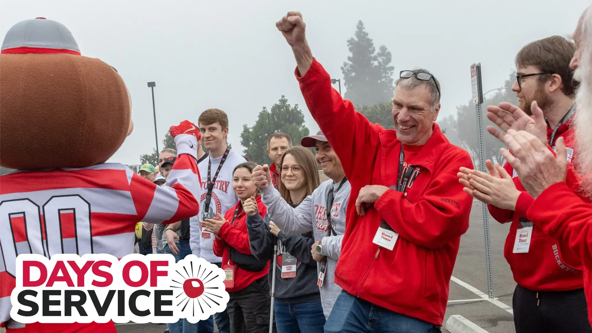 brutus buckeye high-fiving a man wearing a scarlet shirt