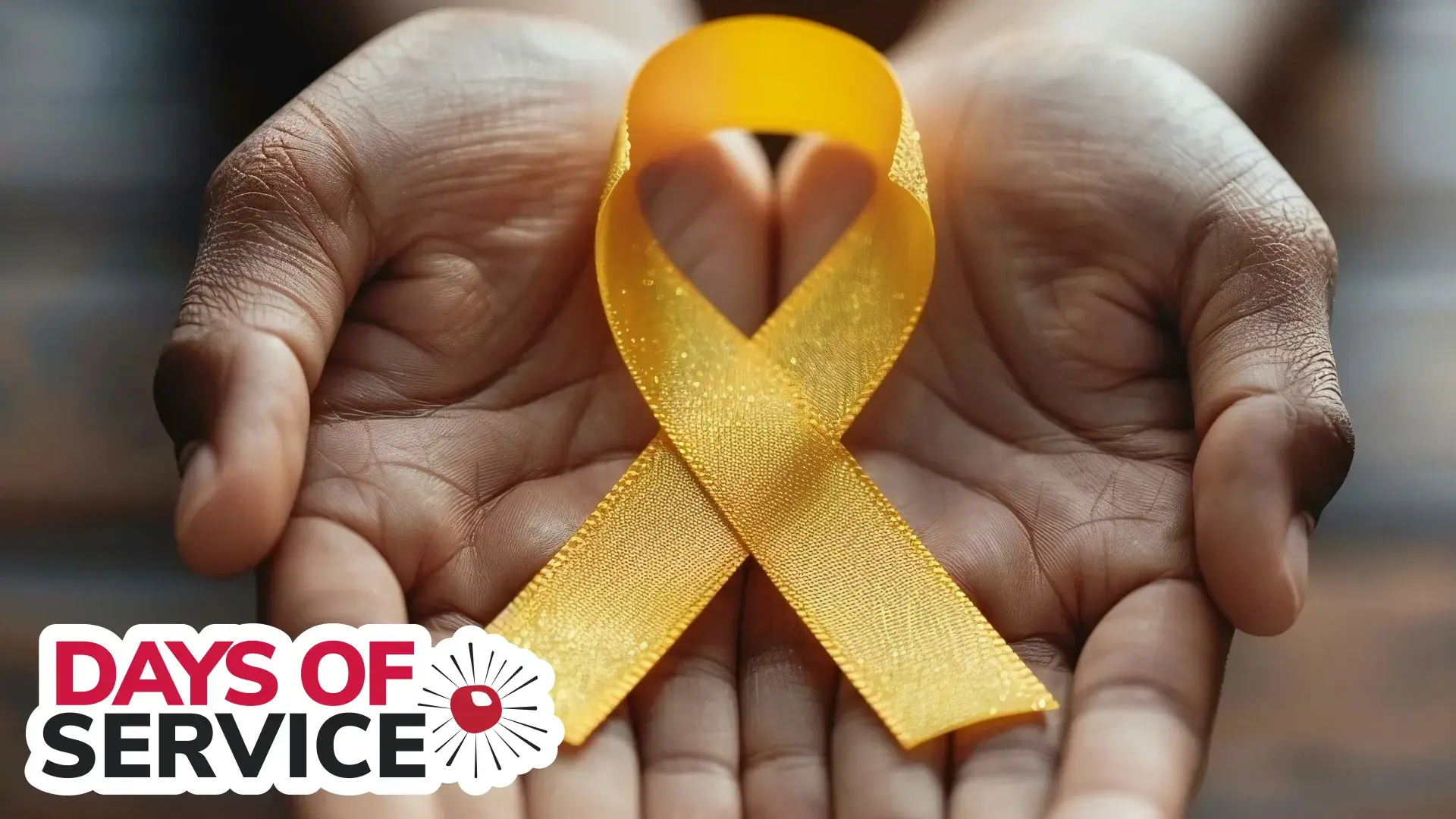 hands holding a yellow ribbon for childhood cancer