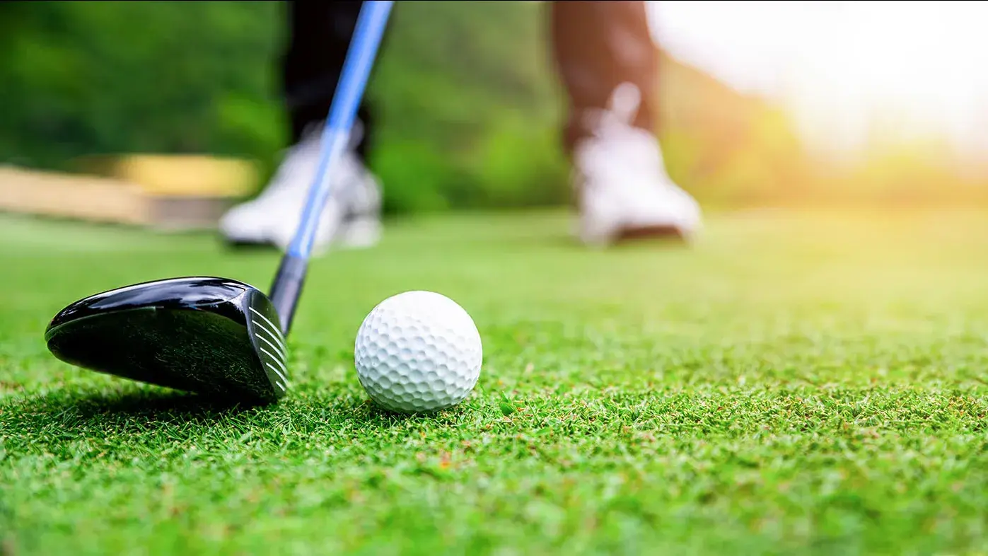 Golf club hitting a golf ball.