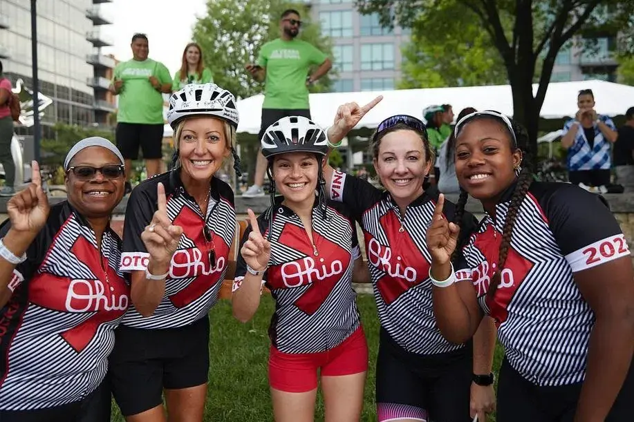 five women in matching pelotonia t-shirts holding up their index figures to represent one goal